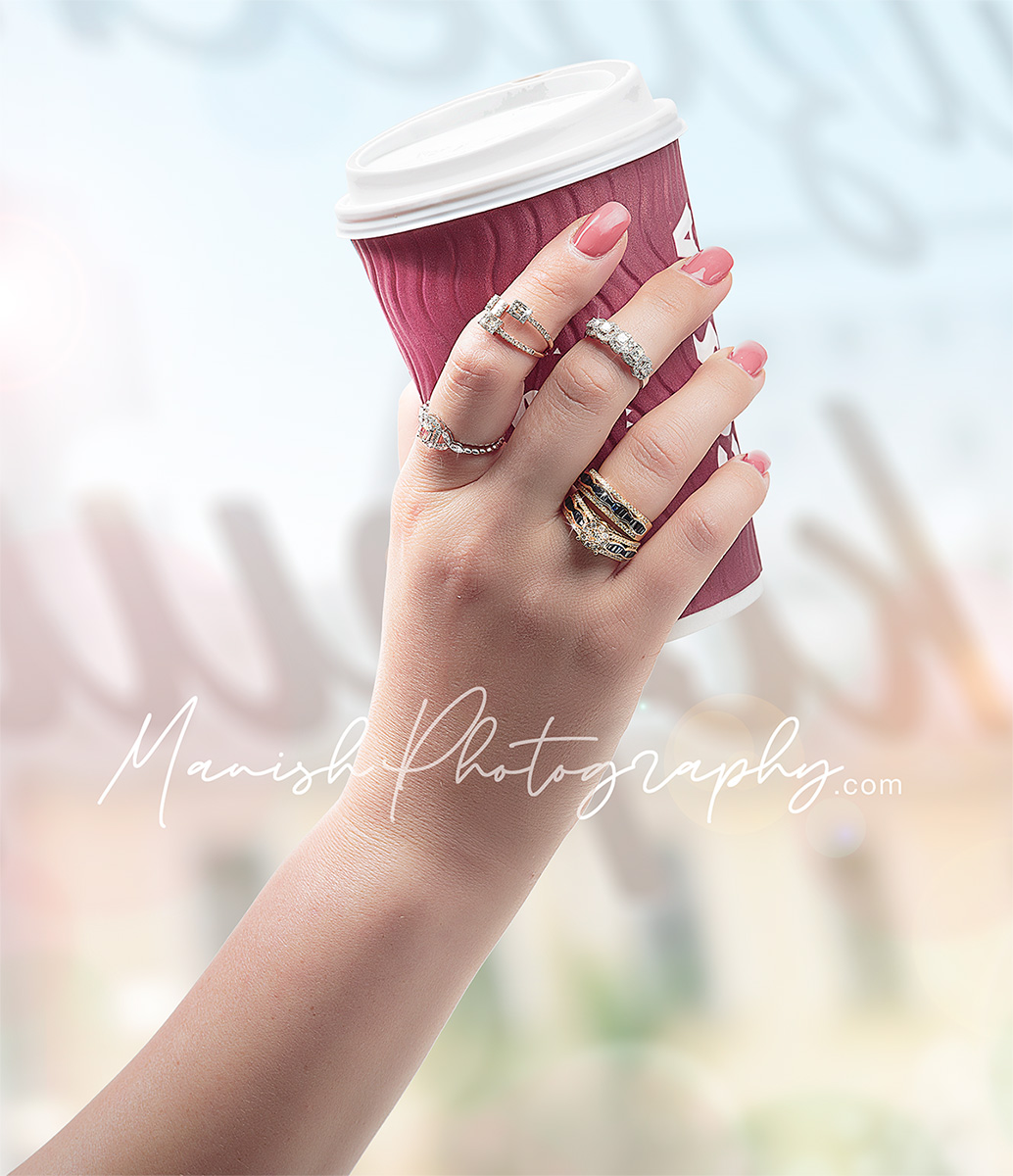 Jewellery studded hand holding a coffee cup